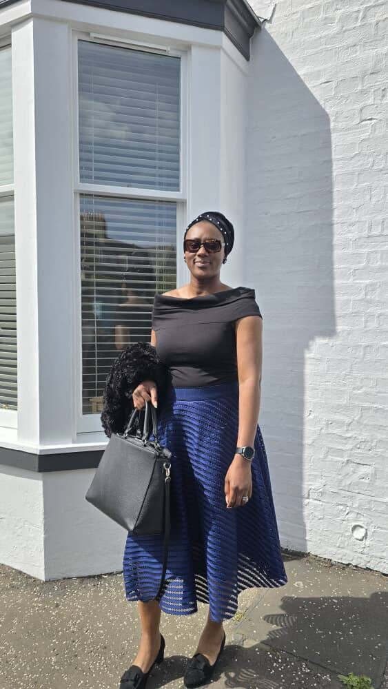 Omowunmi in a navy pleated skirt and off-shoulder top