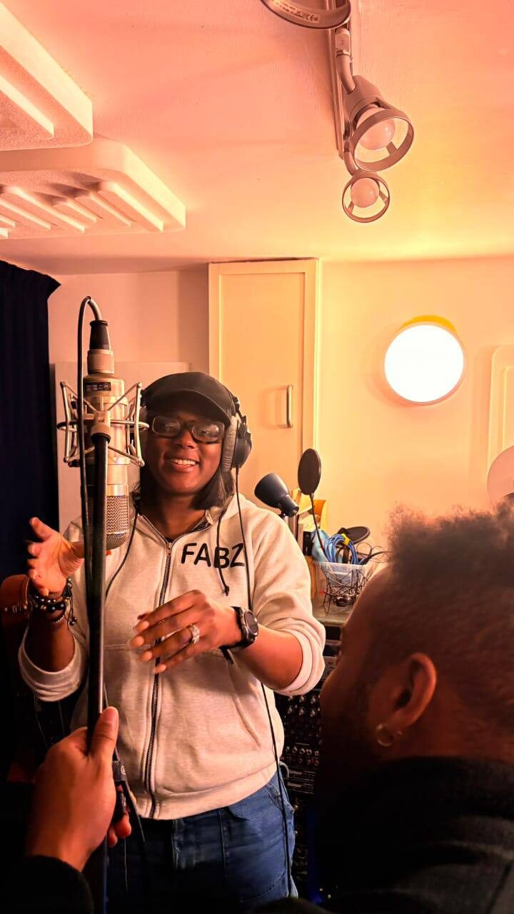 Omowunmi mid-phrase during a recording session, headphones on